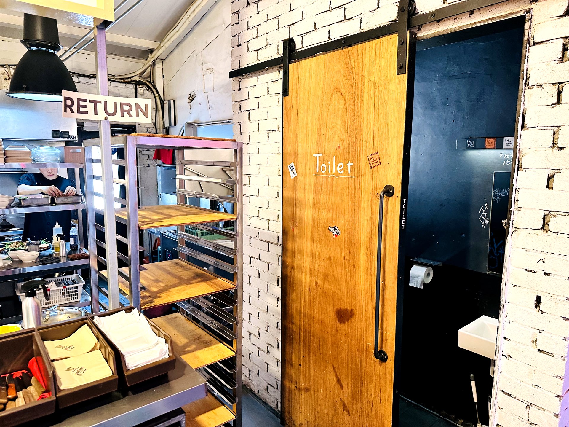 Sliding wooden Toilet door against exposed brick