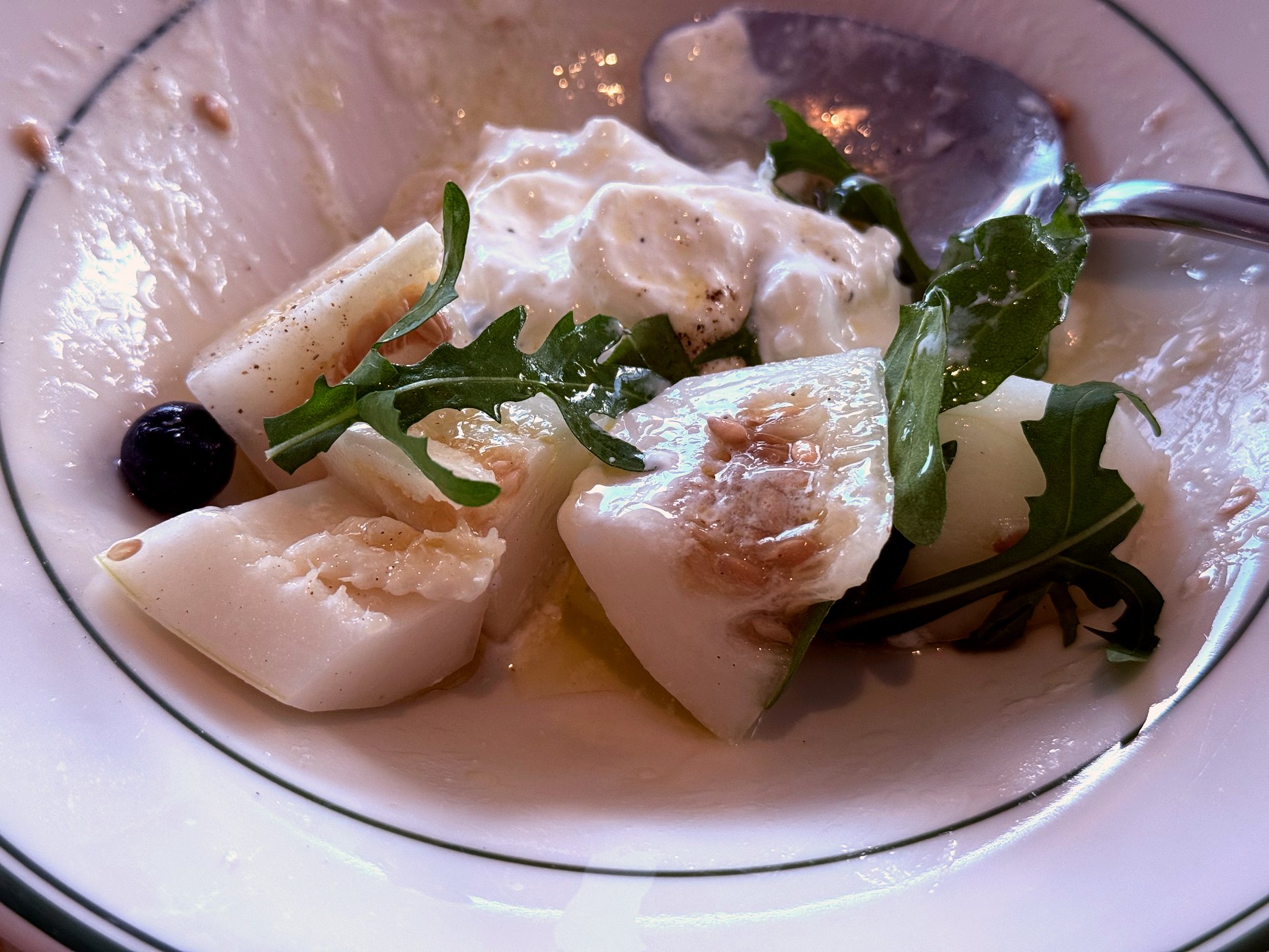 Spring fruit with burrata, arugula, and a blueberry on a fine porcelain plate