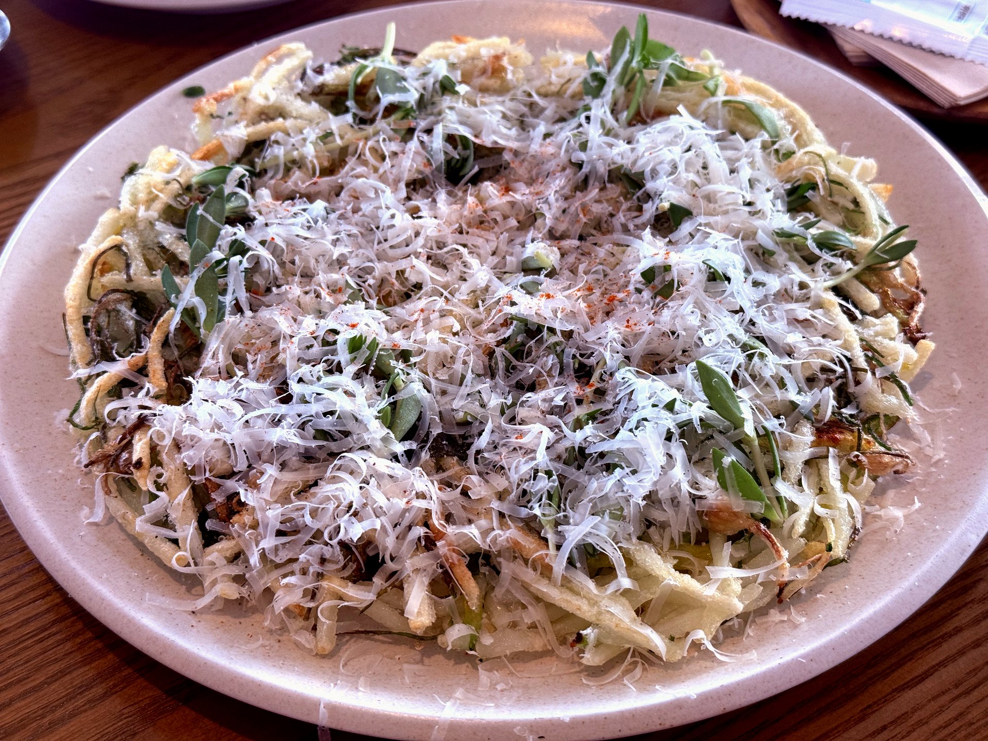 Korean namul pancake topped with thick grated hard cheese and chopped greens