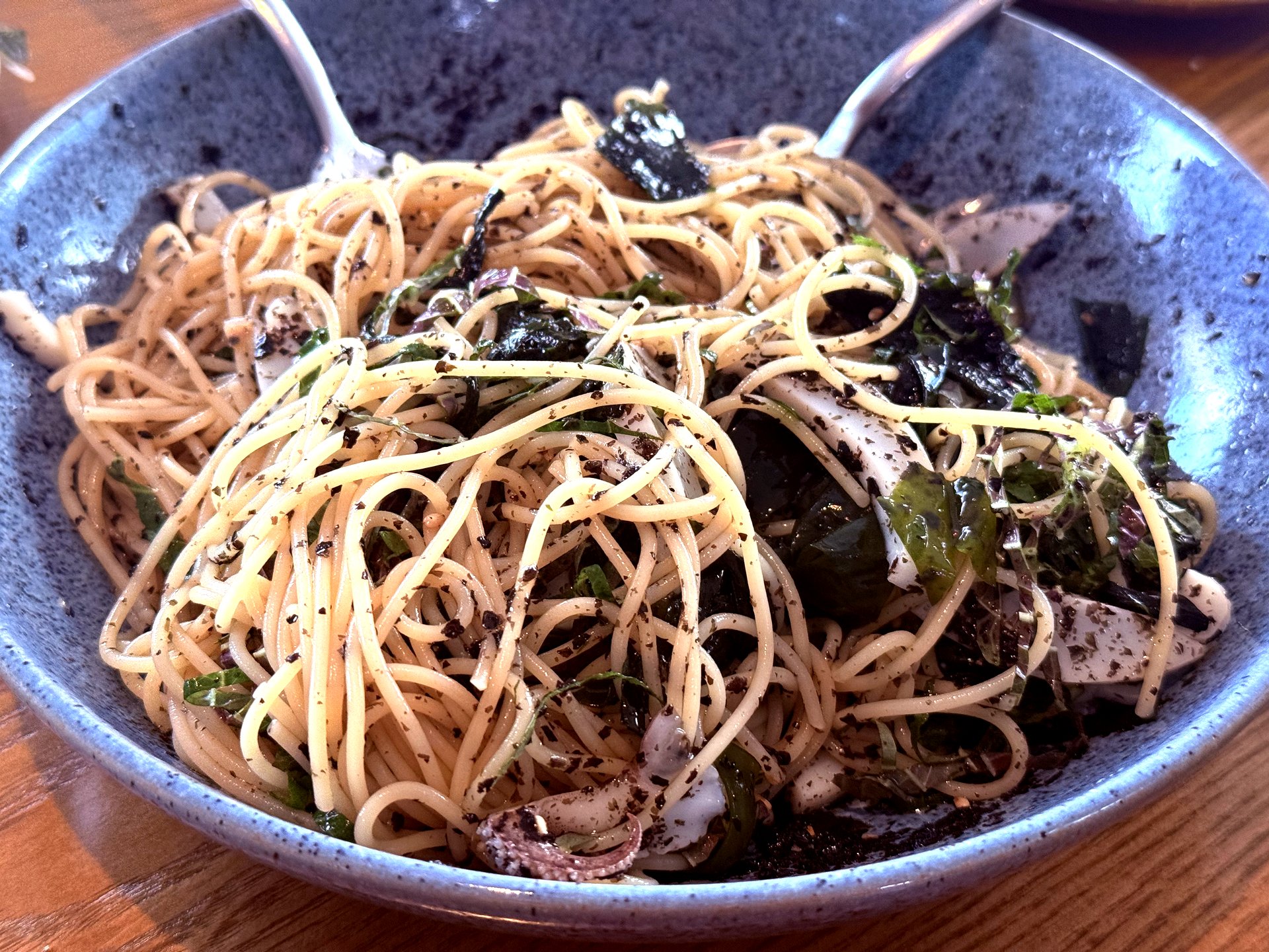Capellini after mixing - cuttlefish slices visible, dark seaweed coating noodles