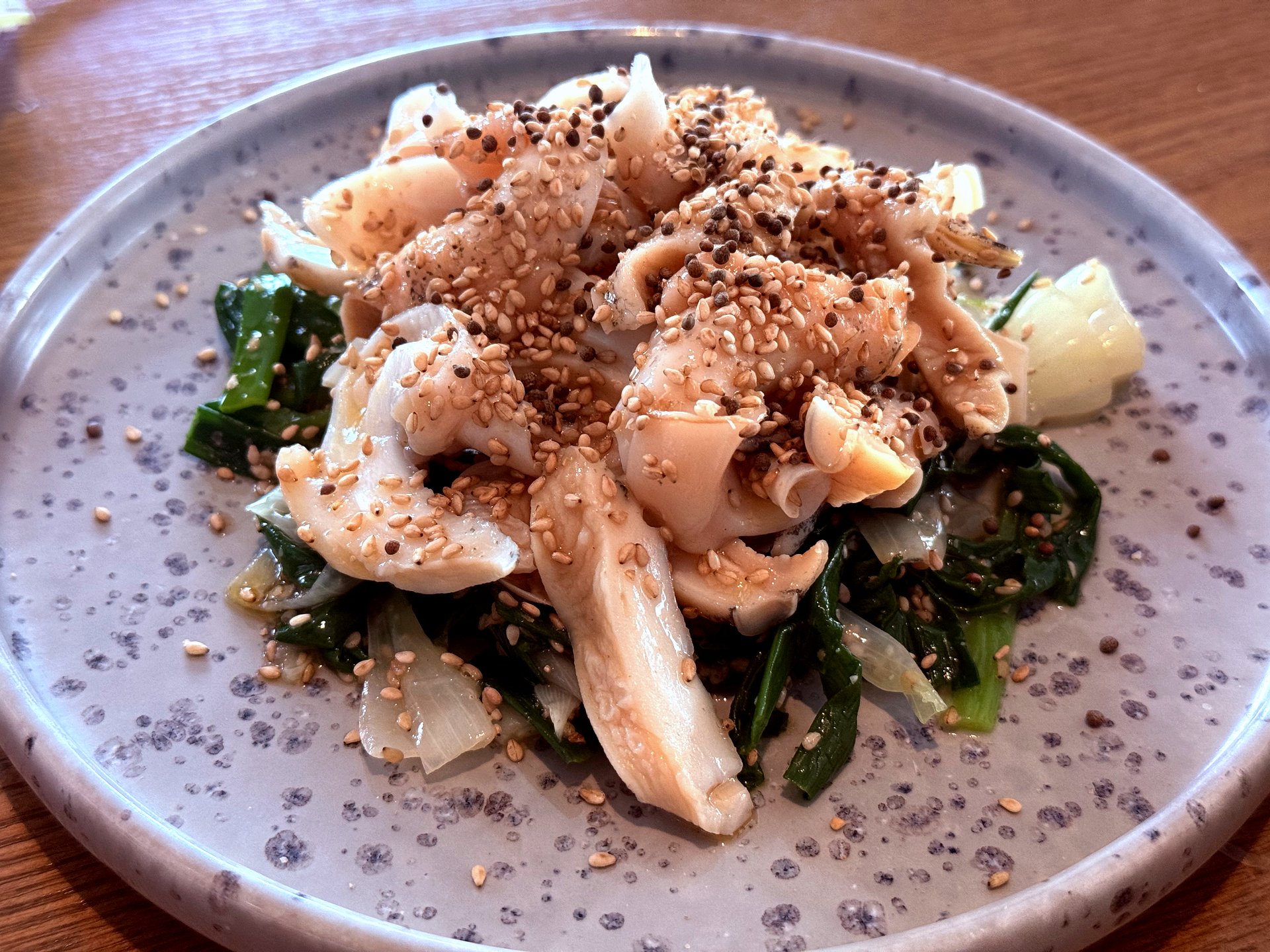 Sliced spring webfoot octopus on green namul base with sesame seeds
