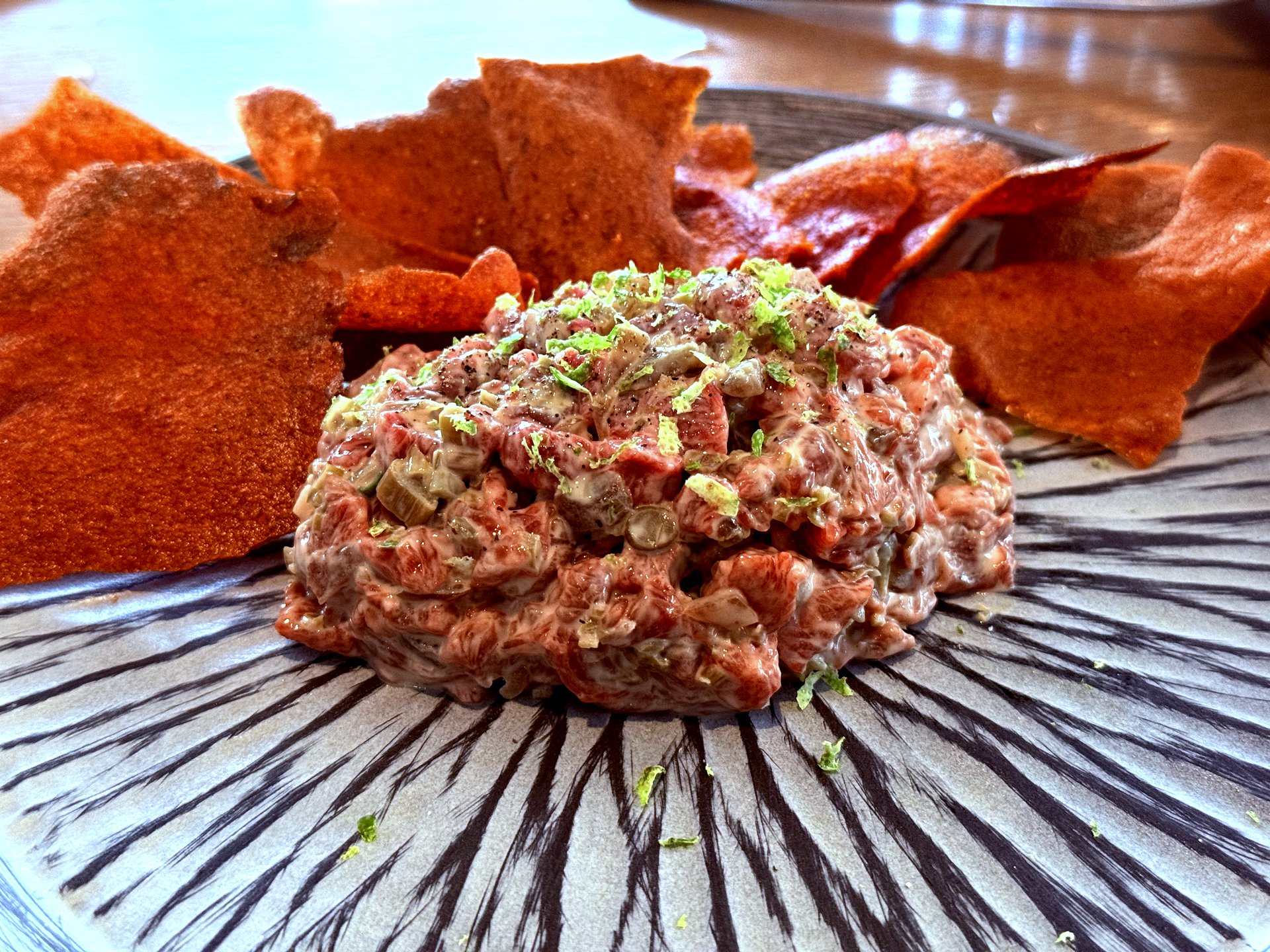 Hanwoo tartare mound surrounded by thin red tomato chip wafers