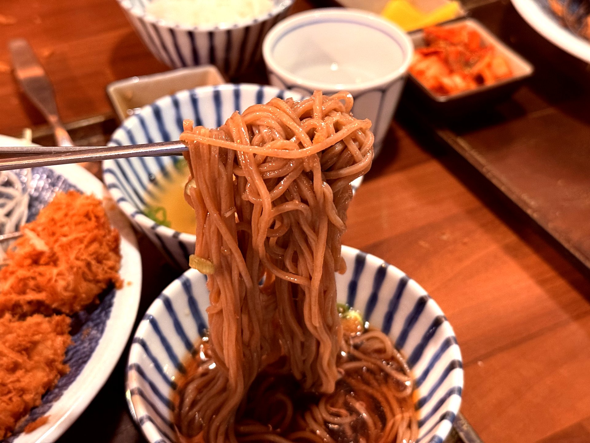 Buckwheat soba noodles lifted with chopsticks at Basak