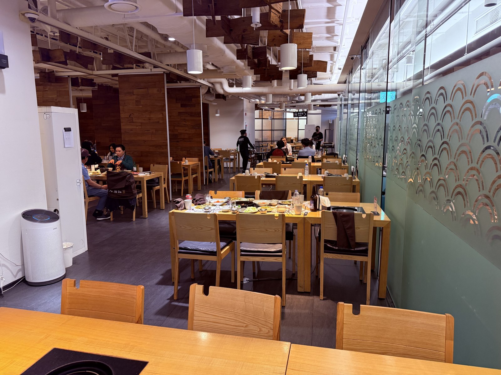Daedo Sikdang Mapo dining room - wide wooden tables, glass partition, light-wood interior