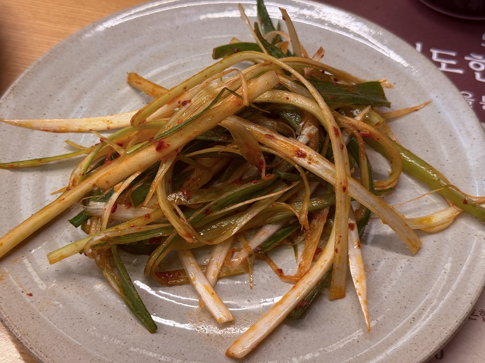 Pa-jeori - slivered green onion salad with red pepper flakes on white plate