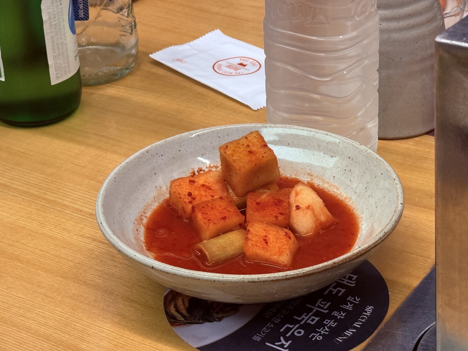 Kkakdugi - diced radish kimchi cubes in red brine in stone bowl
