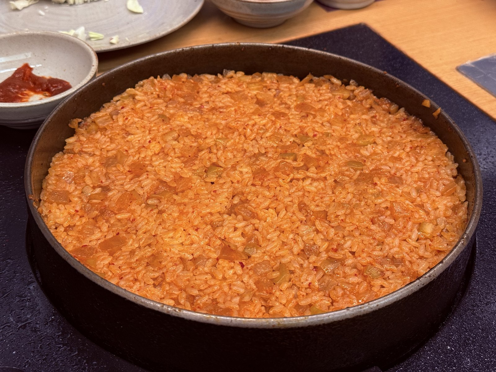 Kkakdugi bokkeumbap - radish kimchi fried rice spread flat in cast-iron pan, getting crispy on bottom