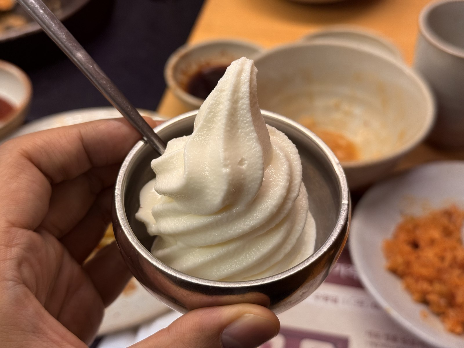 Stainless-steel cup of vanilla soft serve held in hand - the complimentary finisher at Daedo Sikdang Mapo