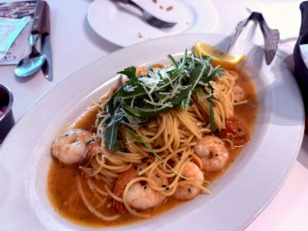 Spaghettini with several shrimp, arugula, lemon, parmesan in a wide oval bowl