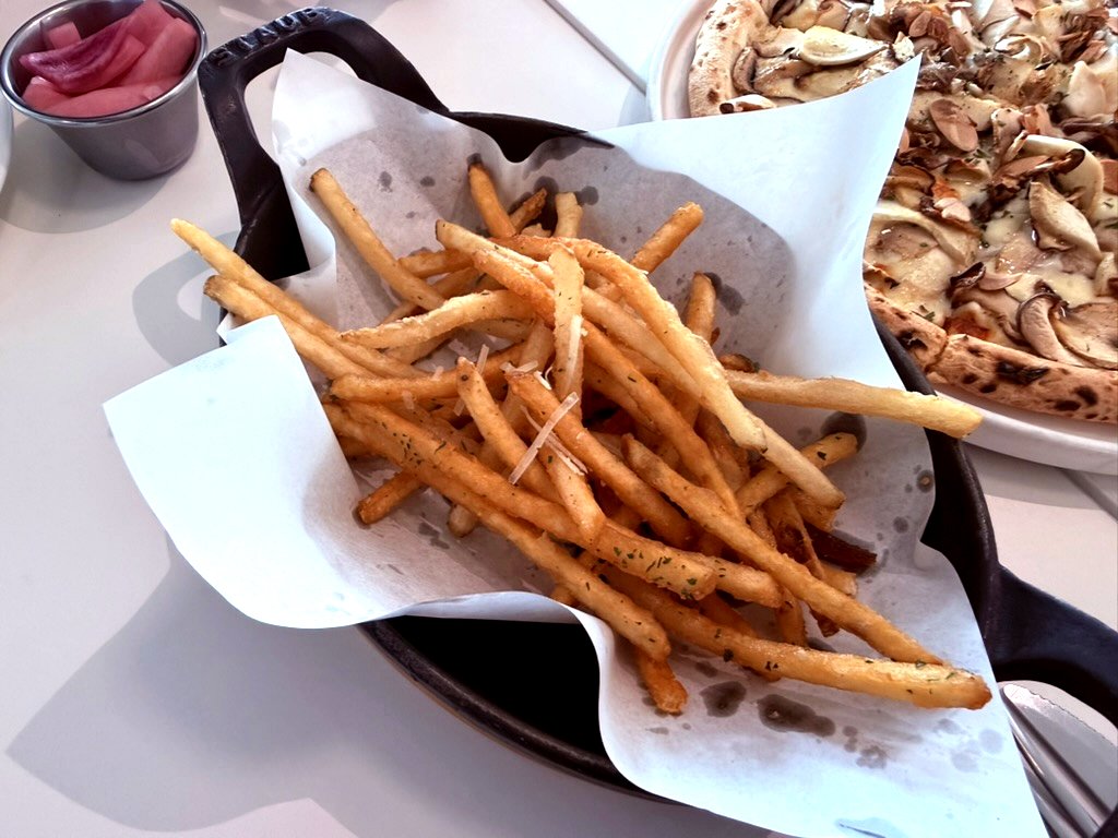 Thin-cut french fries in a cast iron skillet with pickled onions on the side