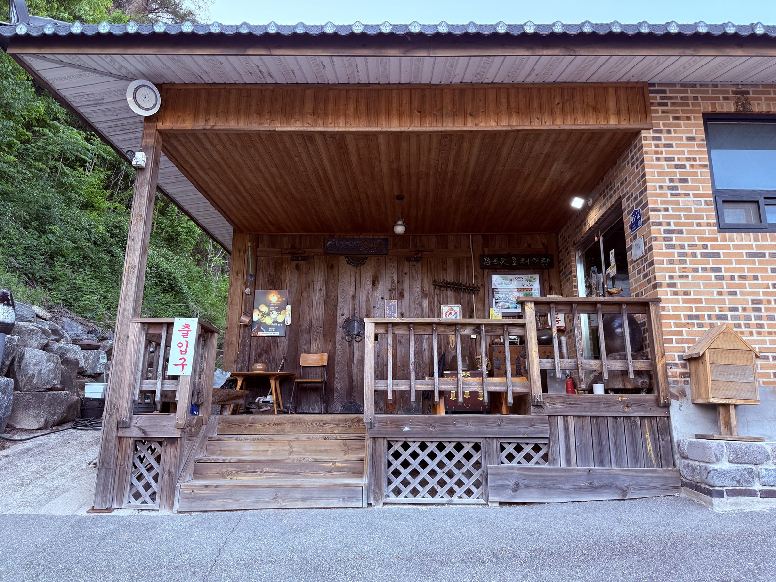 Eondeokwie Jangdokdae wooden porch entrance - traditional Korean tile roof, brick wall, dongdongju rice-wine banner hanging on the door, wooden steps and railings