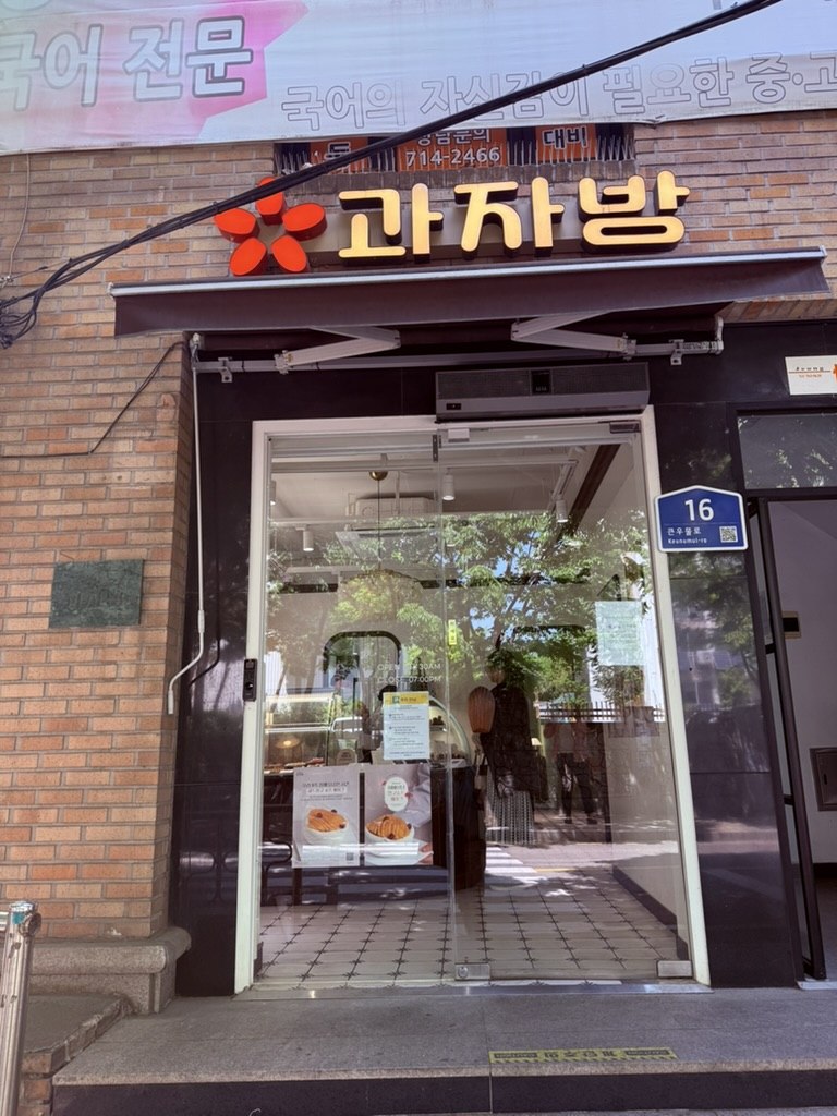 Gwajabang shopfront - orange '과자방' signage over glass entrance with wooden door