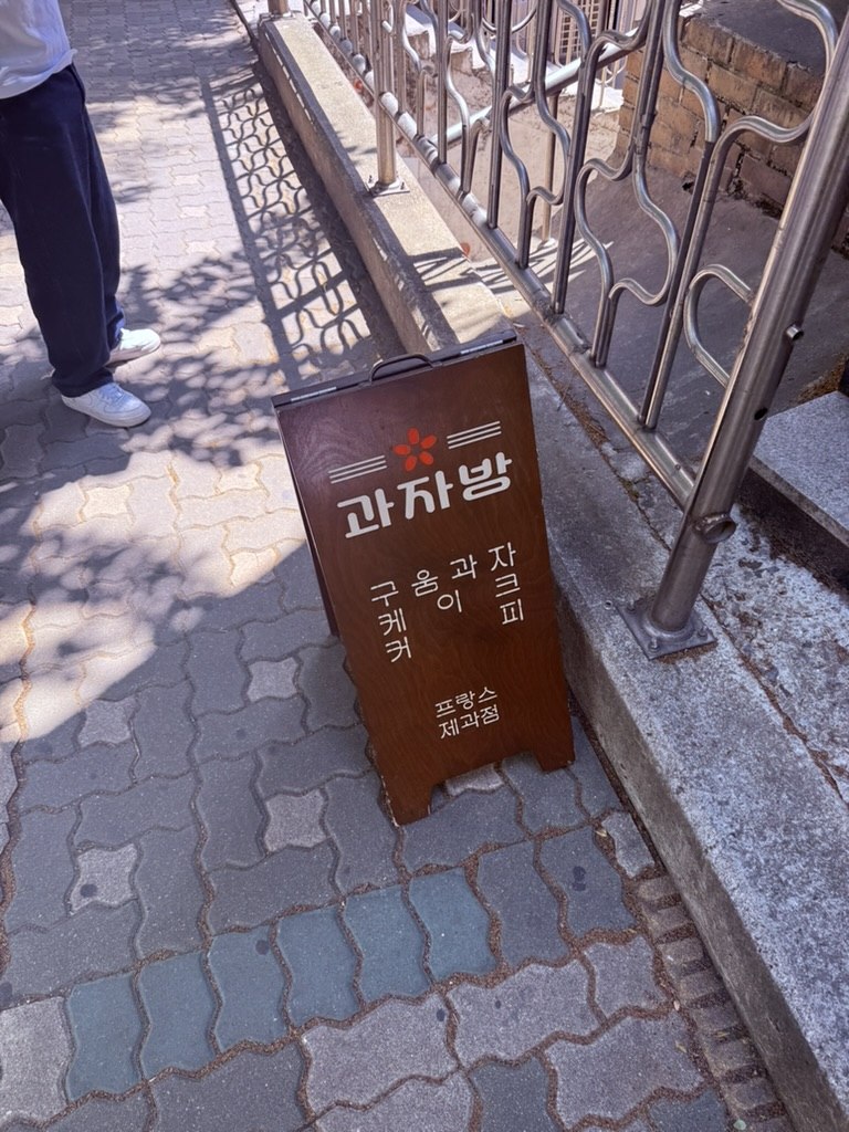 Wooden A-frame sandwich-board sign for Gwajabang on Yeonnam side street, with menu hand-painted in Korean