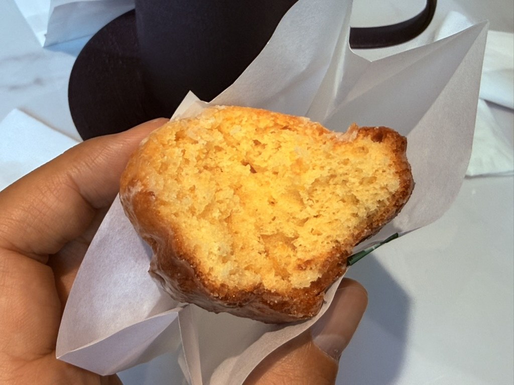 Half-eaten Gwajabang madeleine showing dense golden-yellow crumb and glaze coating, held in hand