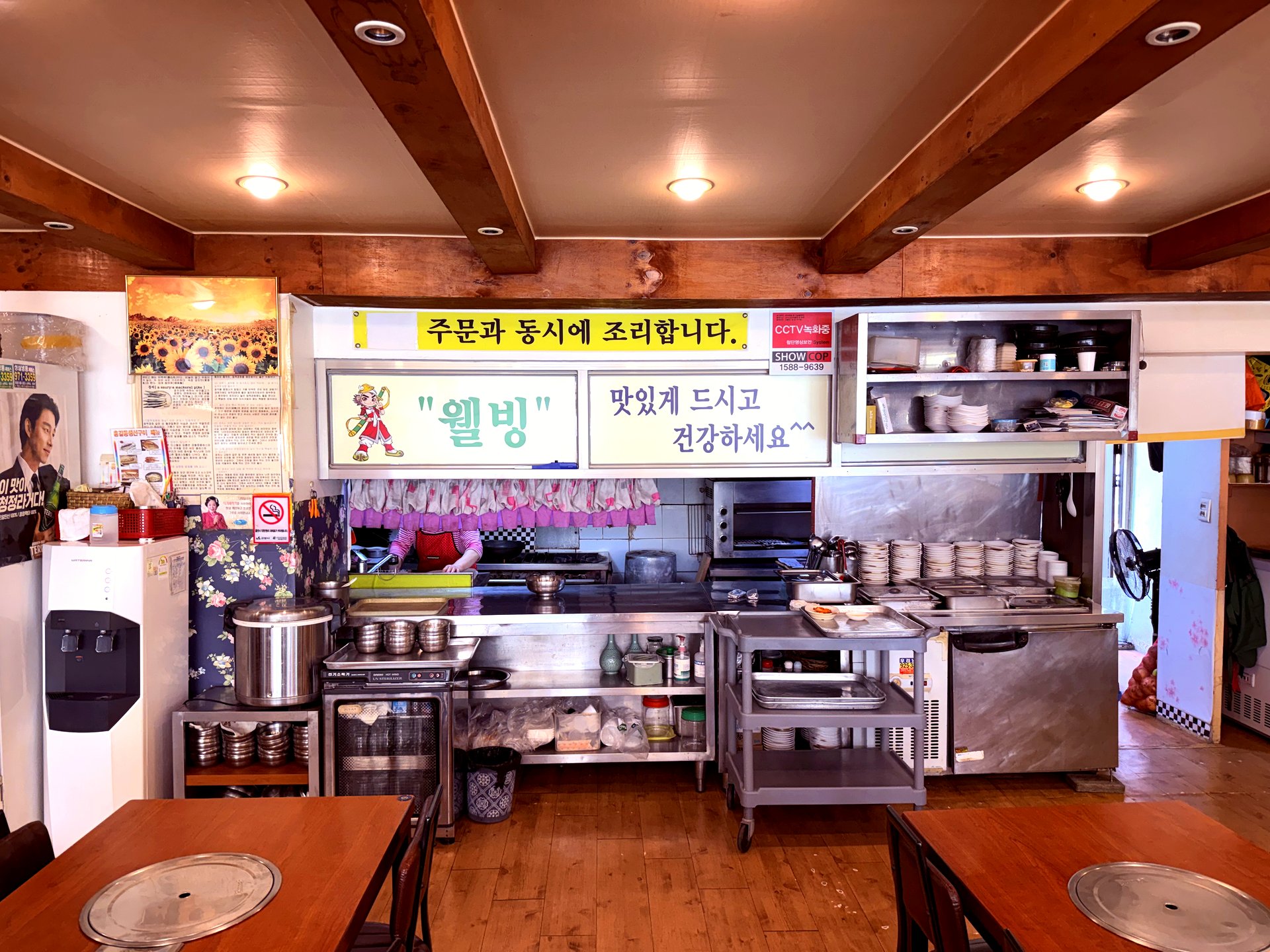 Inside dining room - open kitchen visible behind counter, family-style tables