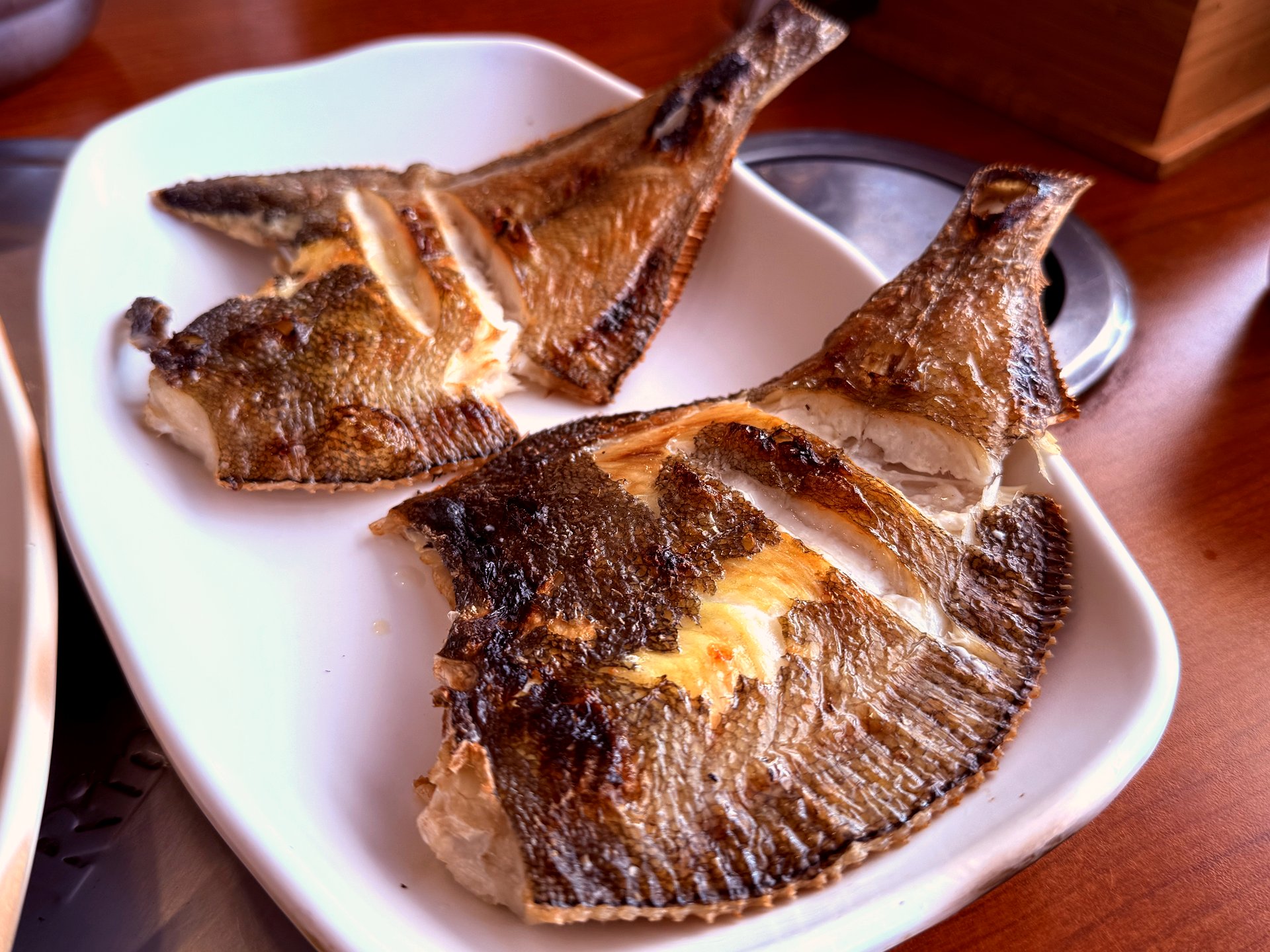 Two pieces of grilled gajami flatfish on a plate with golden-brown crispy skin
