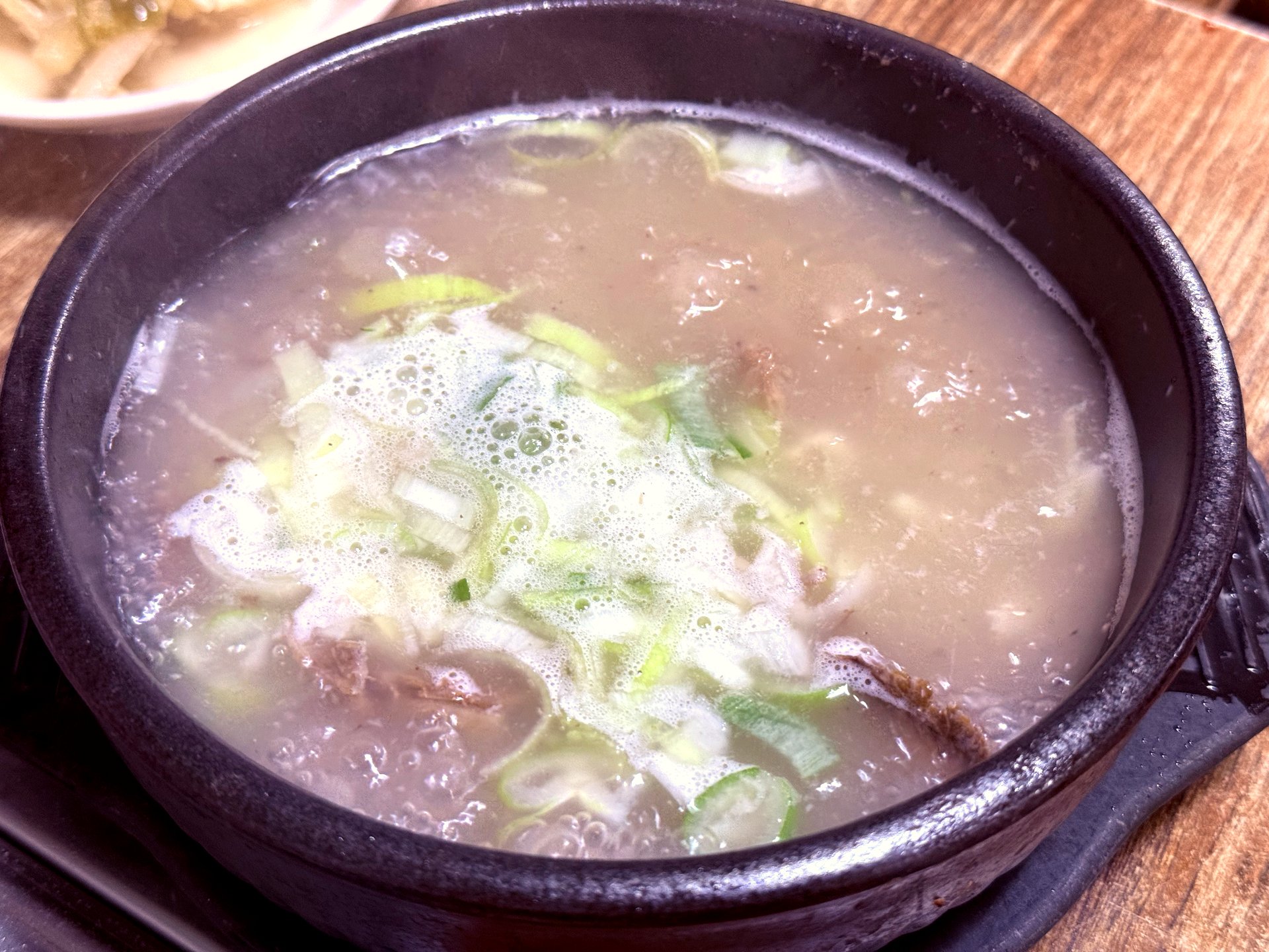 Galbitang in stone bowl with scallions and clear bone broth