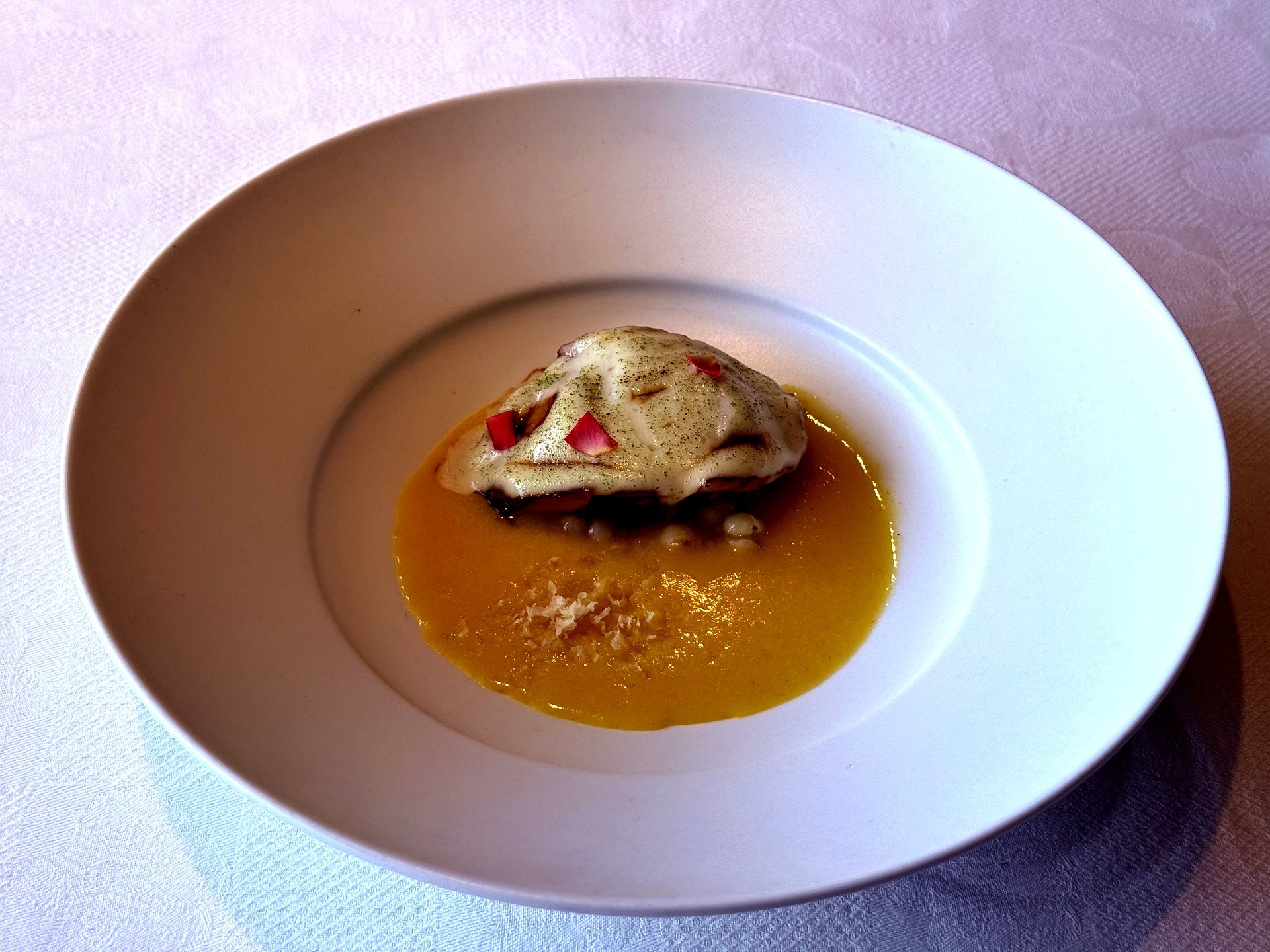 Grilled abalone in saffron-yellow butter sauce with white sauce drizzle