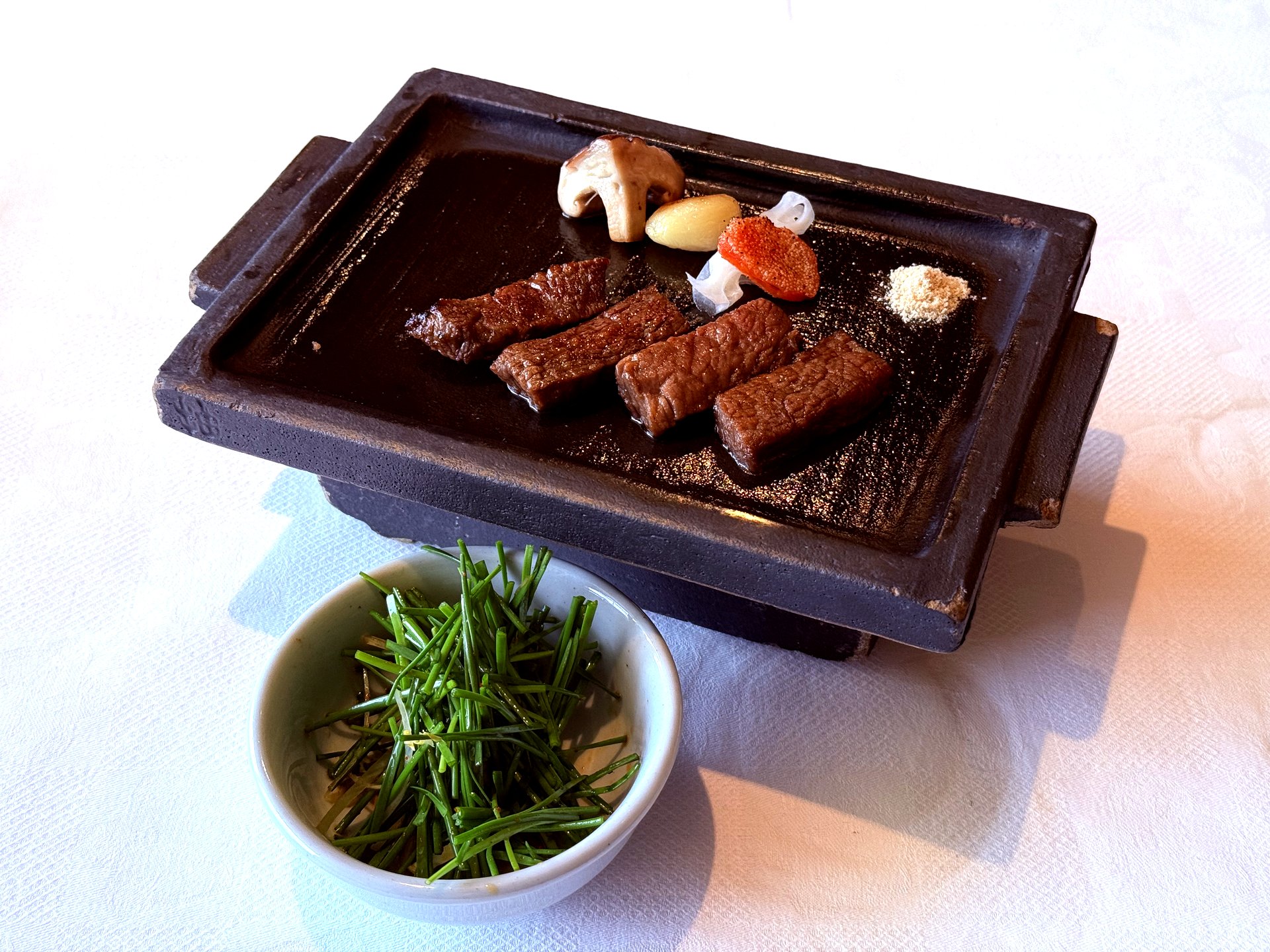 Hanwoo tenderloin slab with bowl of finely-sliced raw chives alongside