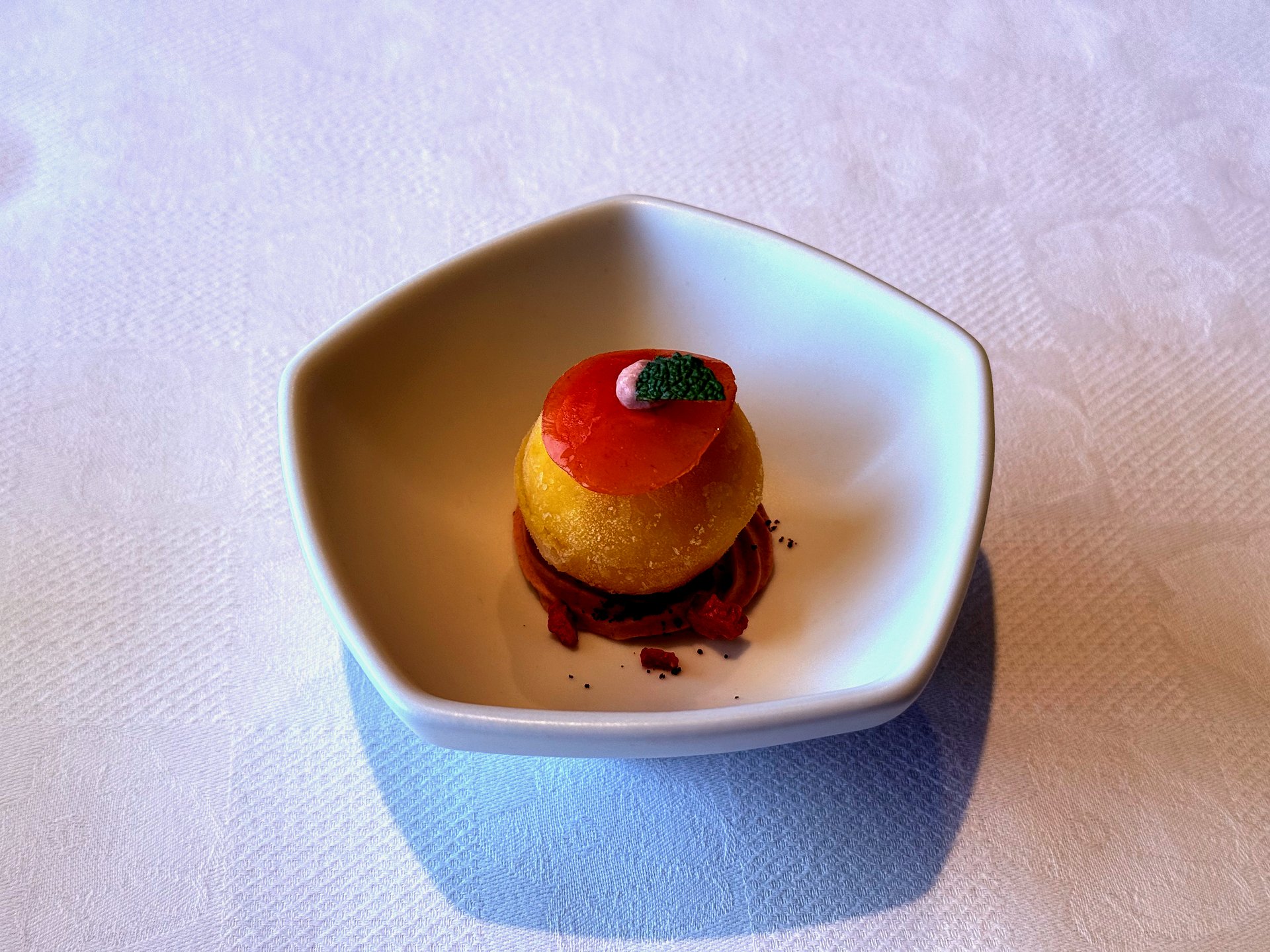 Yuzu mango ice cream dome with red wafer and ganache on hexagonal plate