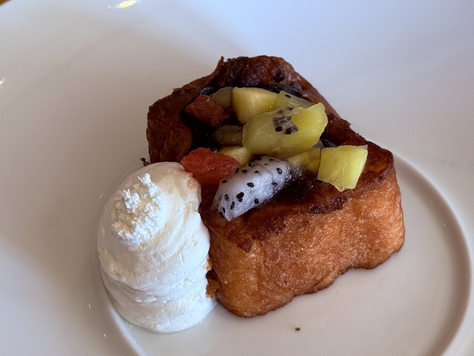 French toast plated with fresh fruit (dragonfruit, kiwi, grapefruit) and vanilla ice cream scoop