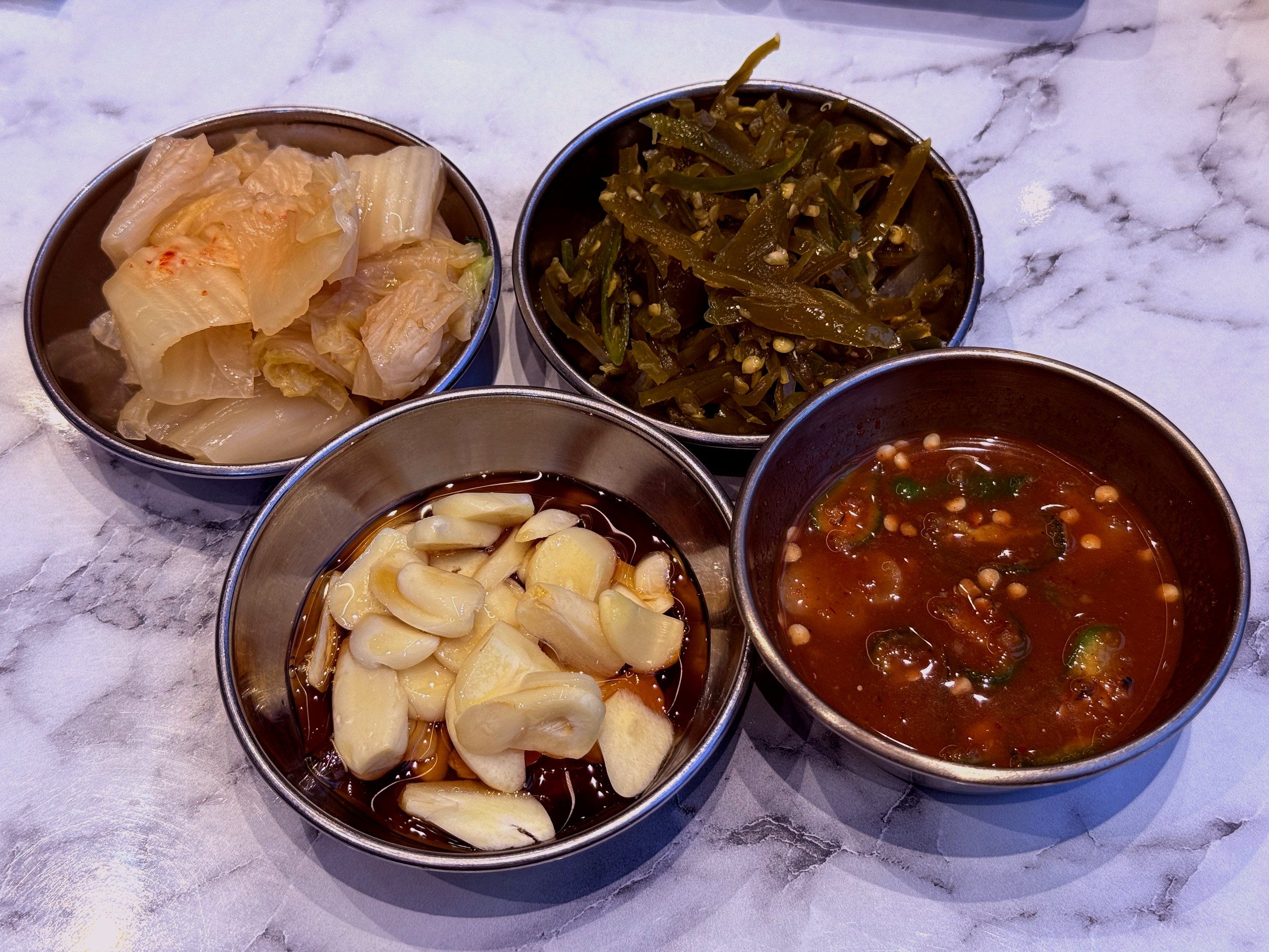 Banchan four-set: kimchi, garlic-soy, jeotgal-style relish, seaweed