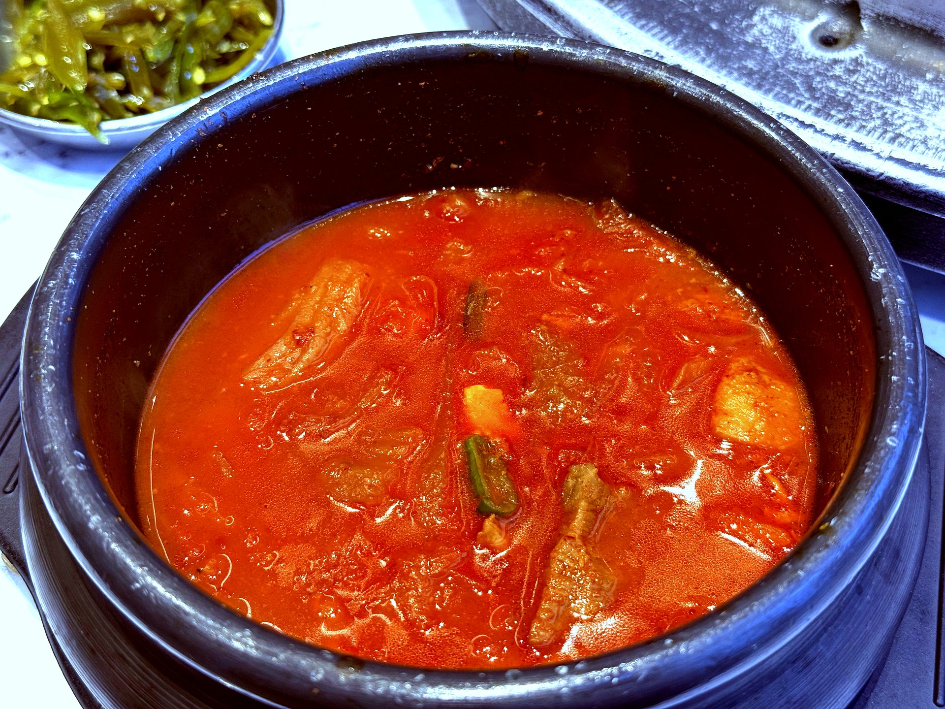 Complimentary kimchi-jjigae stew that arrives with the table