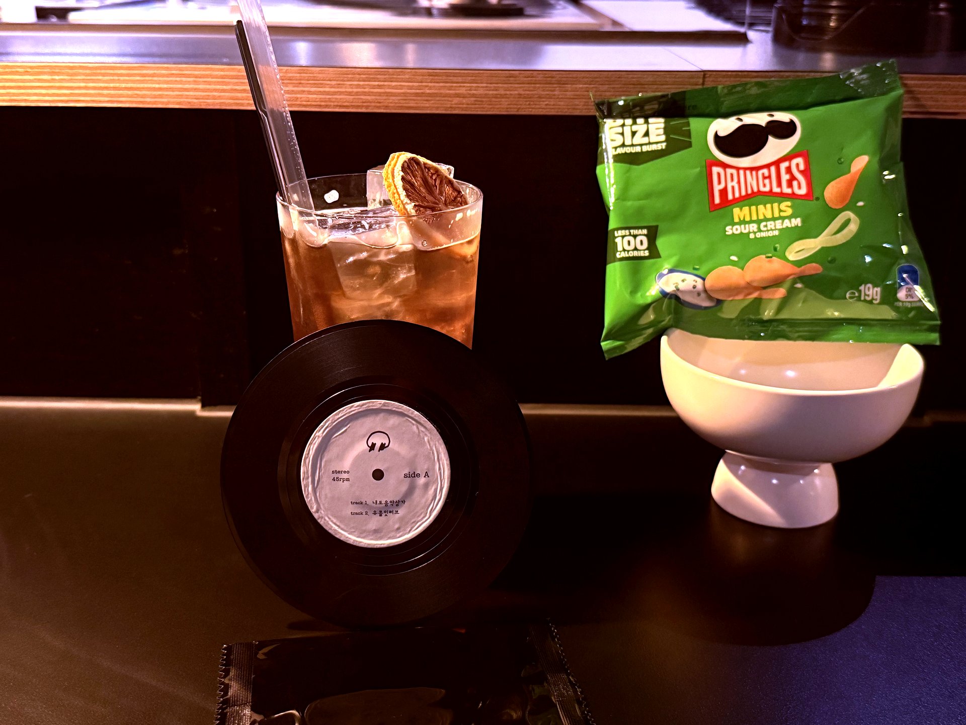Highball with dehydrated orange, 7-inch record, snacks on the bar
