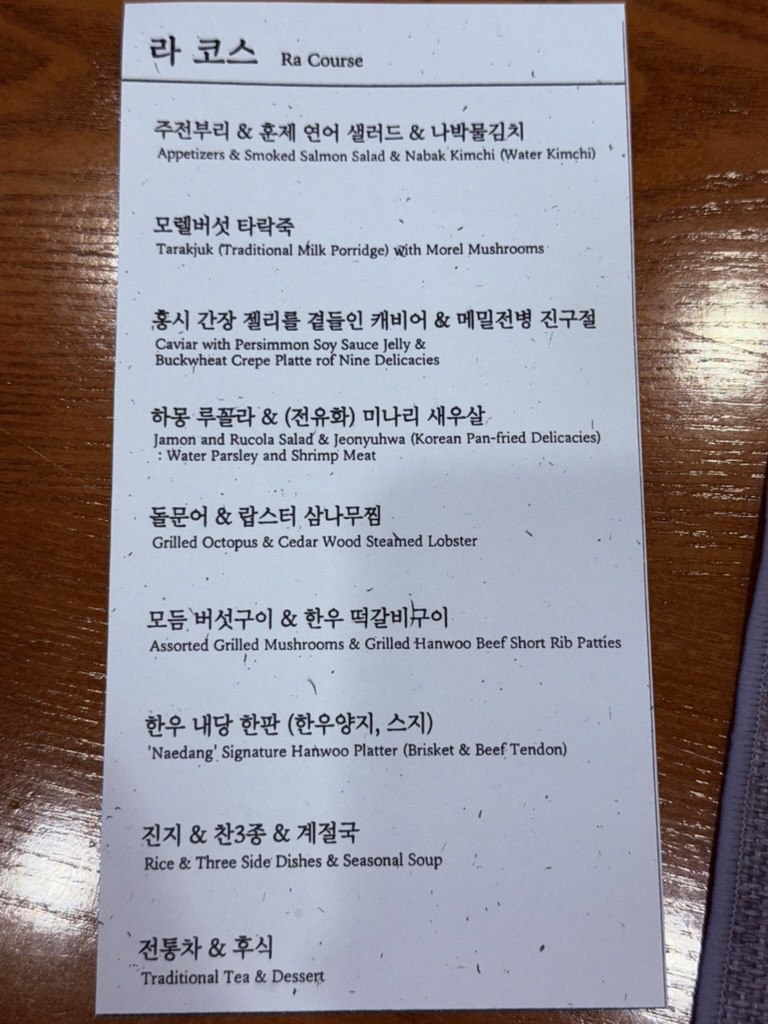 Ra Course menu card at Naedang - bilingual Korean and English listing of all 9 courses including tarakjuk milk porridge, caviar with persimmon soy jelly, buckwheat crepes, jamon and rucola, cedar-steamed lobster, hanwoo tteokgalbi, Naedang signature hanwoo platter, rice and side dishes, and traditional tea with dessert