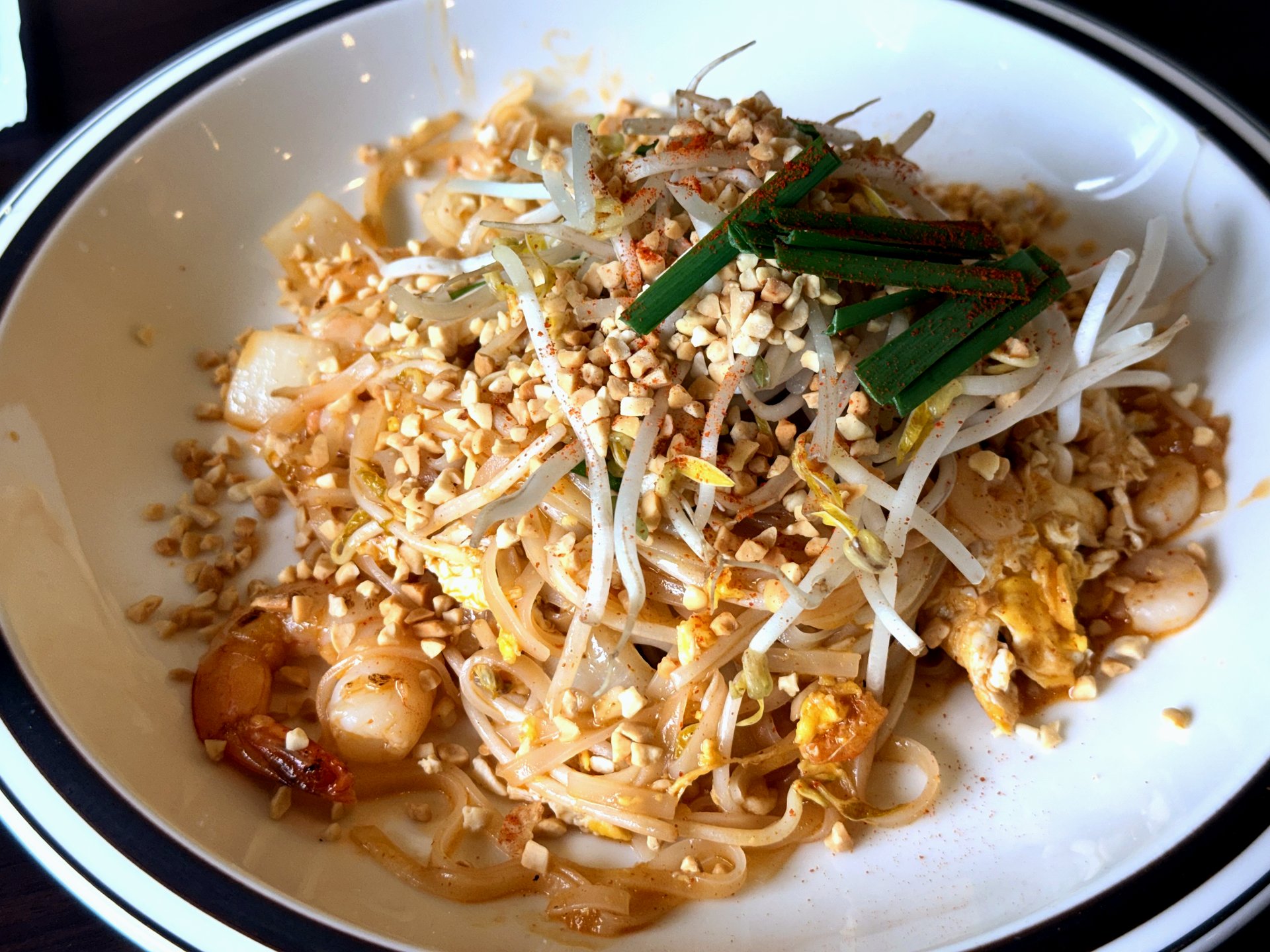 Pad Thai at Pai Deng Yeongjongdo - stir-fried flat rice noodles with shrimp, bean sprouts, garlic chives, scrambled egg and a generous scatter of crushed peanuts and chili powder in a white bowl with a black rim