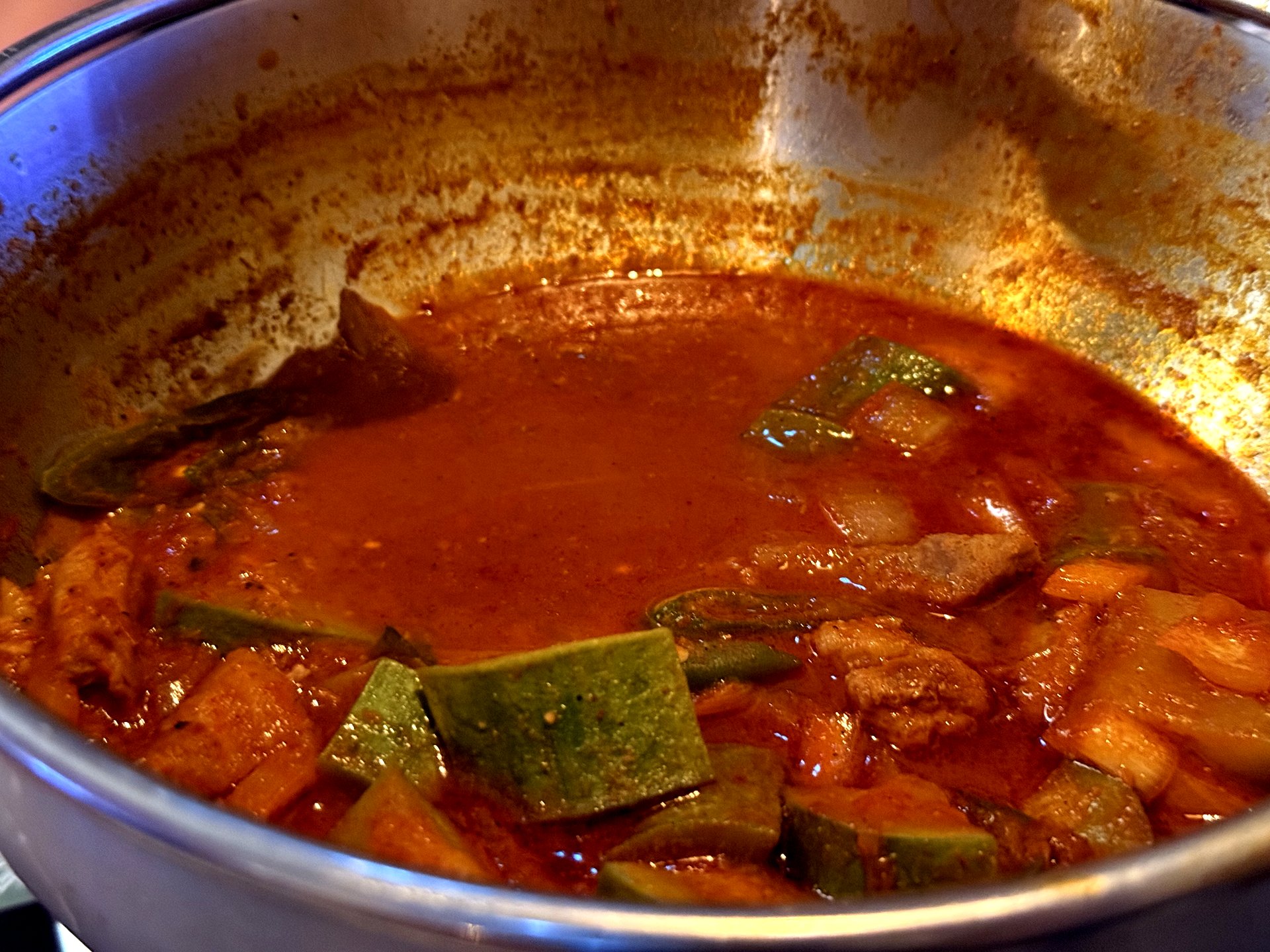 Neurin Maeul Brewery 애호박 고추장찌개 (zucchini gochujang stew) - a stainless-steel pot of bubbling deep-red gochujang stew with slices of green Korean zucchini, onion and pork