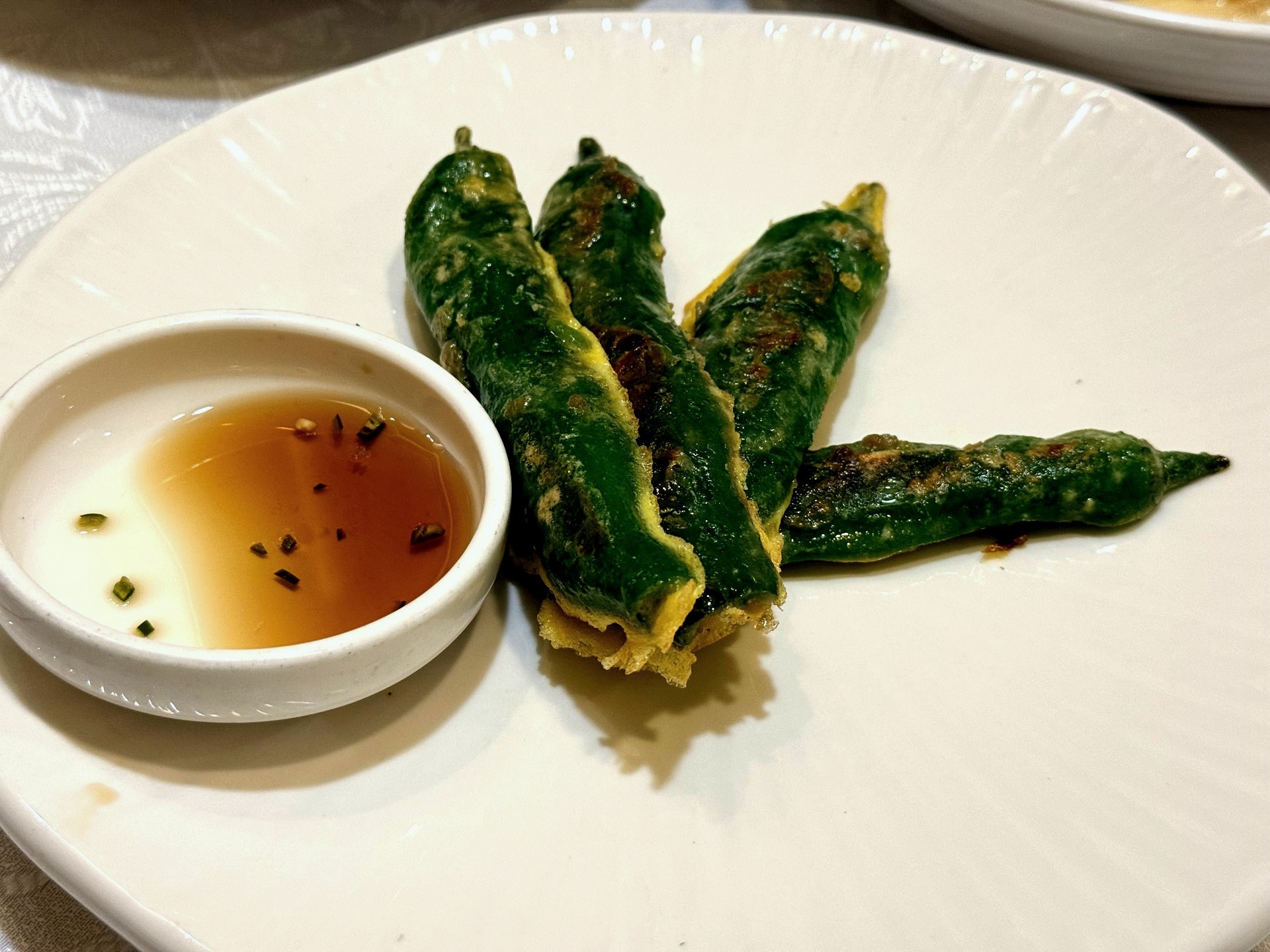 Sudam Hanjeongsik 고추전 (pepper jeon) - green peppers stuffed with seasoned meat-and-tofu filling, coated in egg batter and pan-fried golden, arranged on a white plate beside a small dish of soy dipping sauce