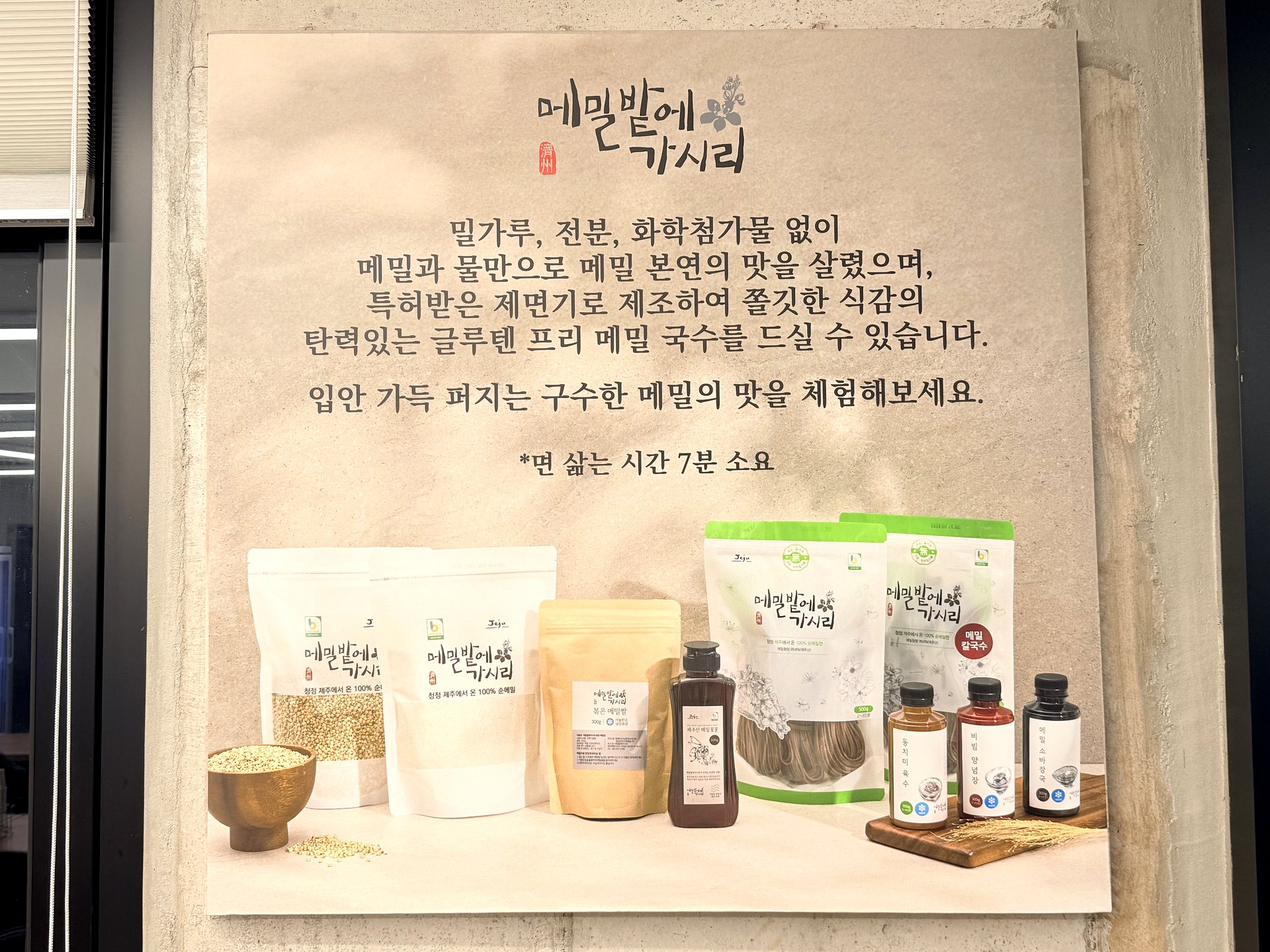 Wall panel at Memilbat-e Gasiri explaining 100% Jeju buckwheat, gluten-free noodles made with no wheat flour, starch or additives, with packaged buckwheat products