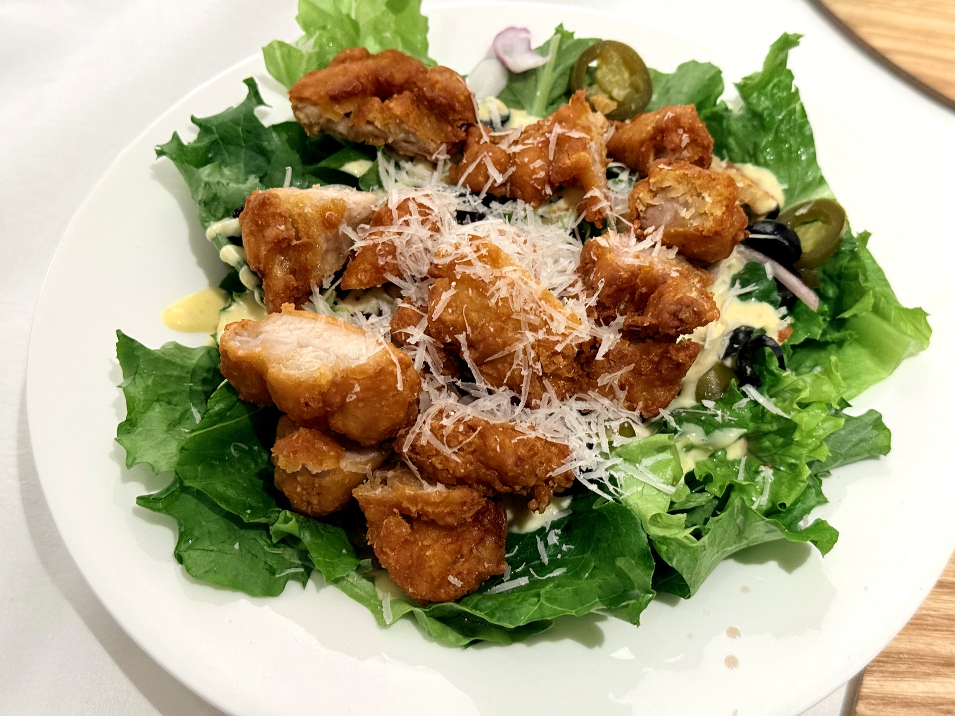 OZ Pizza cajun chicken salad - crunchy cajun-fried chicken chunks over fresh greens with jalapeno, olives, red onion and grated parmesan in a creamy dressing
