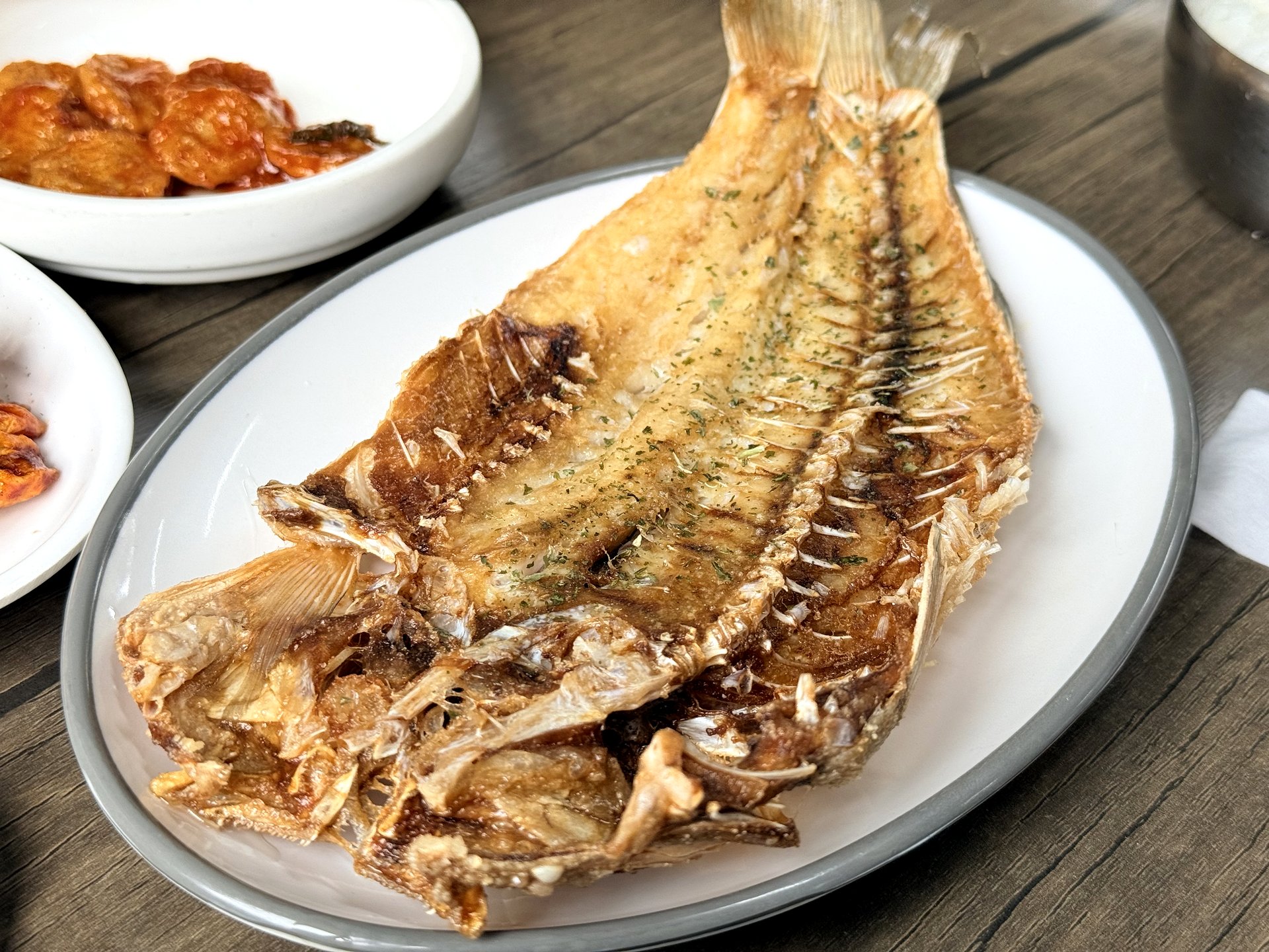Samgeori Sikdang okdom-gui (grilled tilefish) - a whole butterflied tilefish pan-grilled golden and crisp, with clean white flesh, on an oval plate